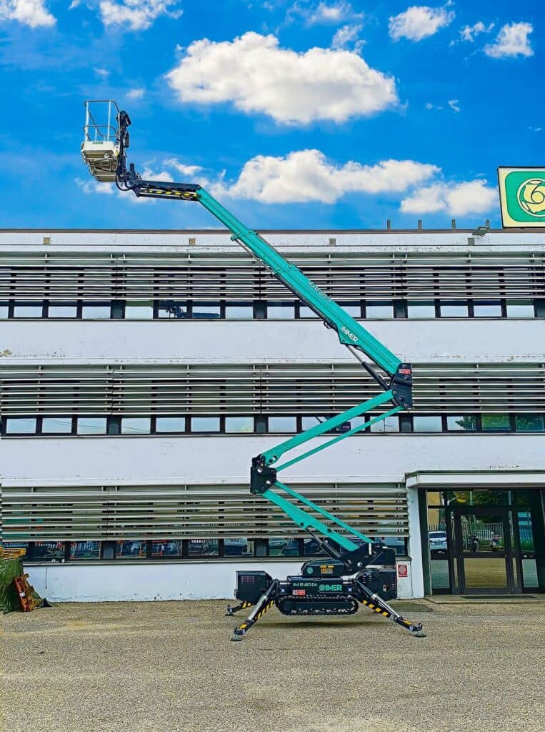 IM R 65 / 20 DA Pro tracked spider lift fully extended beside a three-story building